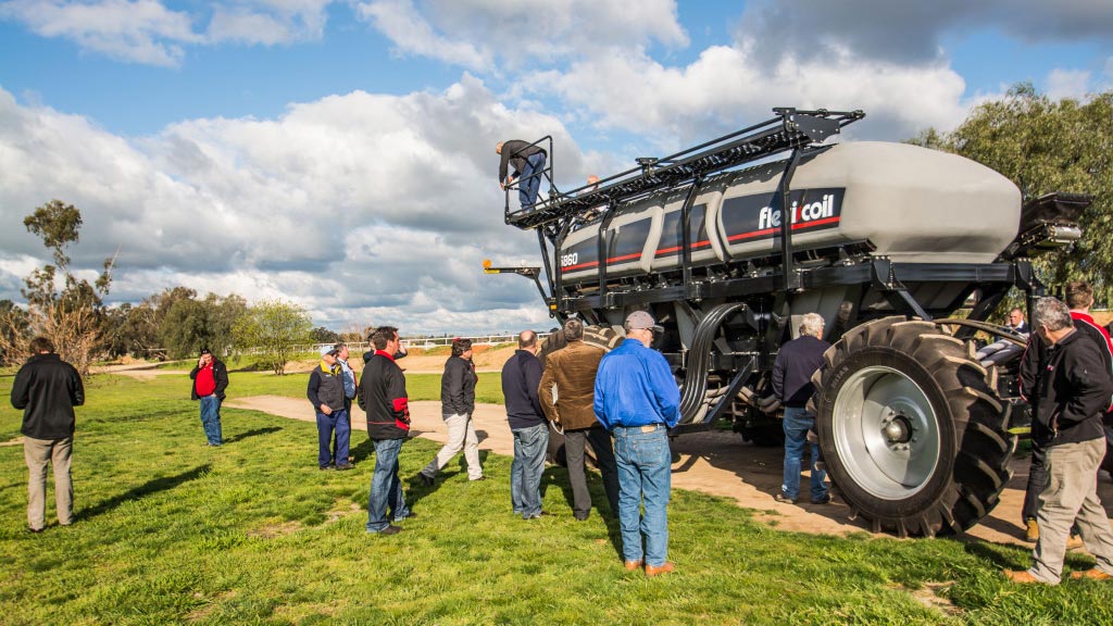 A group of farmers standing in a field looking at a Flexi-Coil 60 Series machine