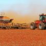 A Flexi-Coil ST820 Precision Cultivator being pulled by a Case IH tractor through a red dusty field