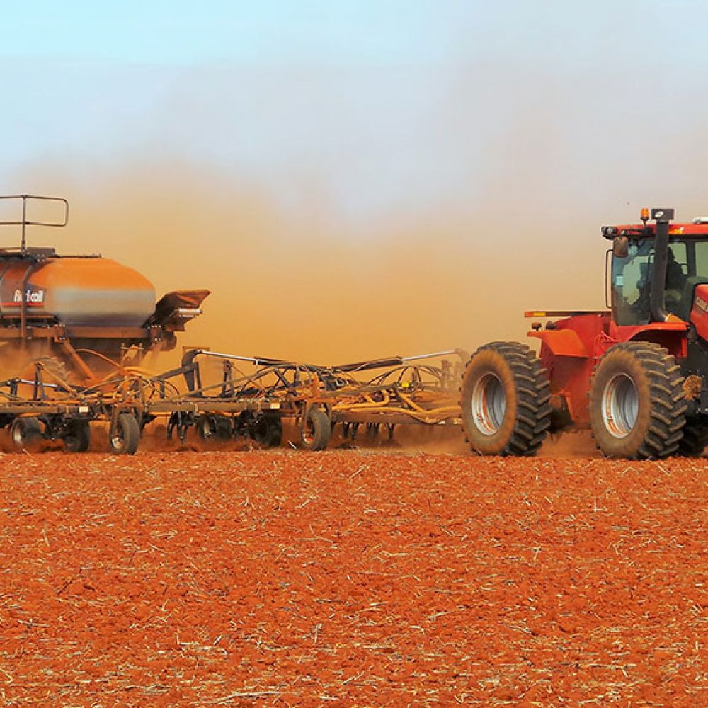 A Flexi-Coil ST820 Precision Cultivator being pulled by a Case IH tractor through a red dusty field
